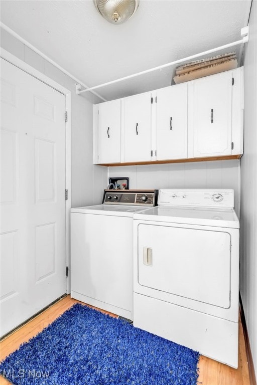 laundry room with light hardwood / wood-style floors, cabinets, and washing machine and clothes dryer