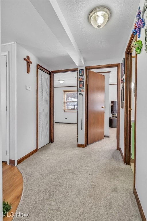 corridor with light colored carpet and a textured ceiling