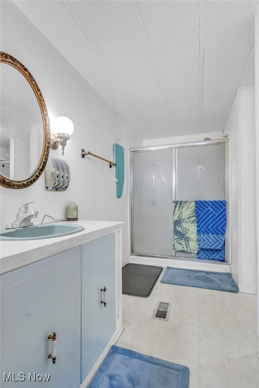 bathroom with vanity and a shower with door