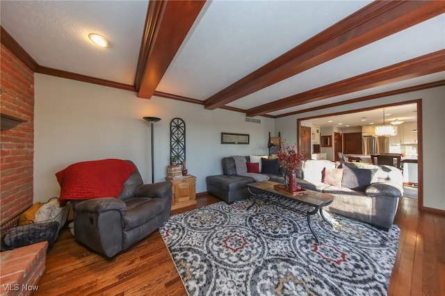 living room with visible vents, ornamental molding, beam ceiling, hardwood / wood-style floors, and an inviting chandelier