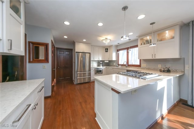 kitchen featuring light stone counters, hanging light fixtures, stainless steel appliances, and white cabinets