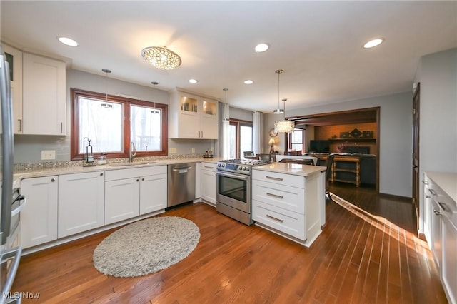 kitchen with a peninsula, stainless steel appliances, light countertops, and a sink