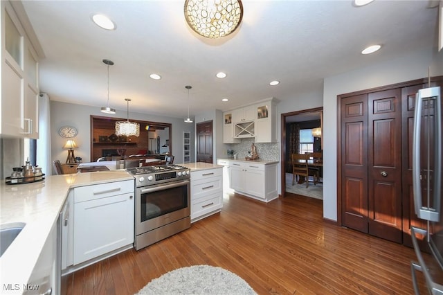 kitchen with white cabinetry, gas range, pendant lighting, hardwood / wood-style floors, and backsplash