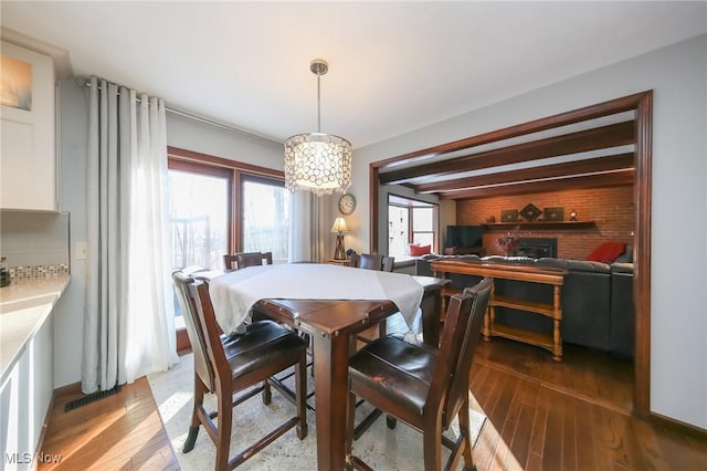 dining space with wood-type flooring and a brick fireplace