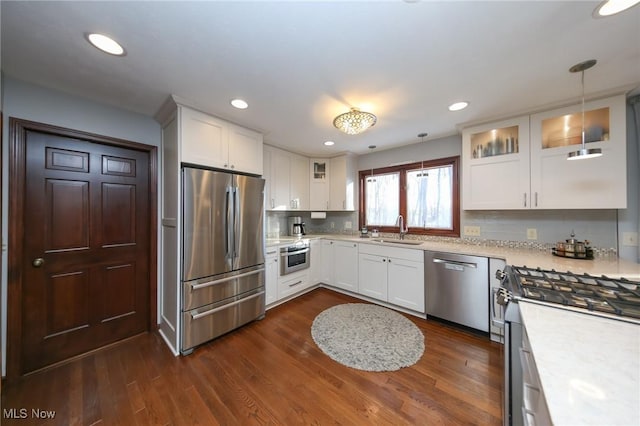 kitchen with dark wood-type flooring, a sink, stainless steel appliances, light countertops, and glass insert cabinets