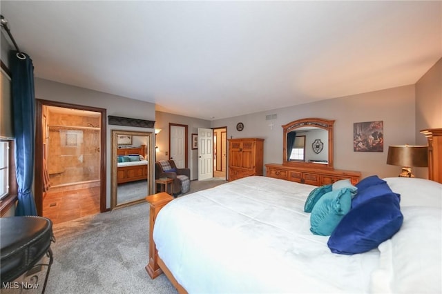 bedroom featuring ensuite bathroom and light carpet