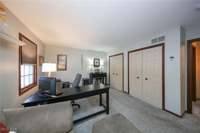 carpeted office space featuring baseboards and visible vents