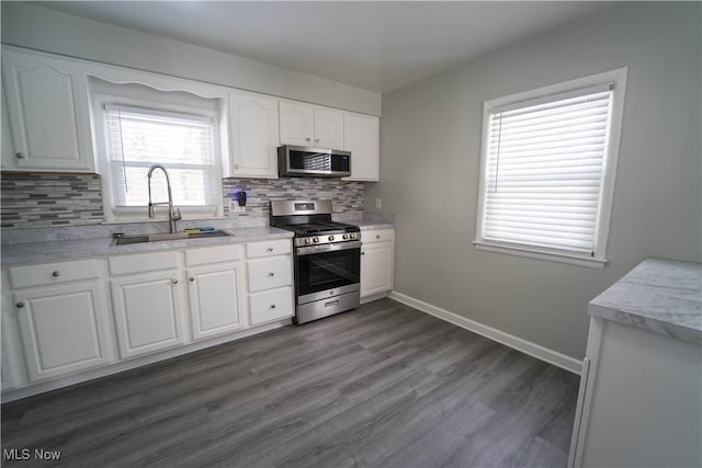 kitchen featuring appliances with stainless steel finishes, dark hardwood / wood-style floors, sink, backsplash, and white cabinets