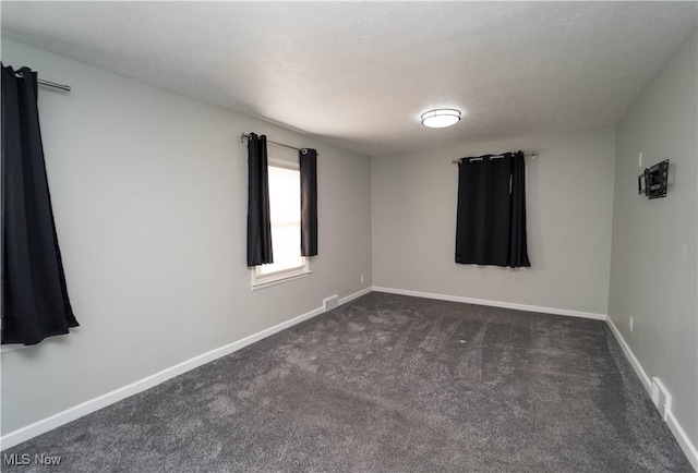 spare room featuring dark carpet