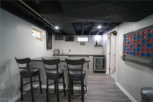 bar with wood-type flooring and beverage cooler