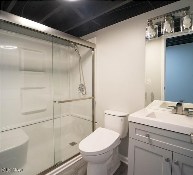 bathroom with wood-type flooring, toilet, a shower with shower door, and vanity