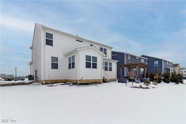 snow covered rear of property featuring a pergola and central AC