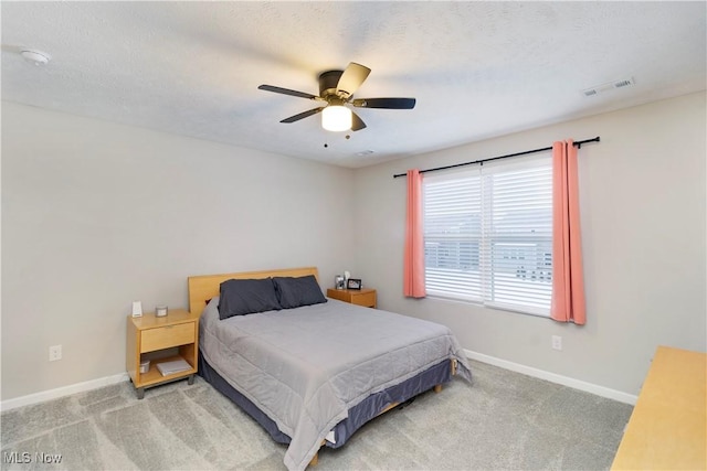 bedroom with ceiling fan, carpet floors, and a textured ceiling