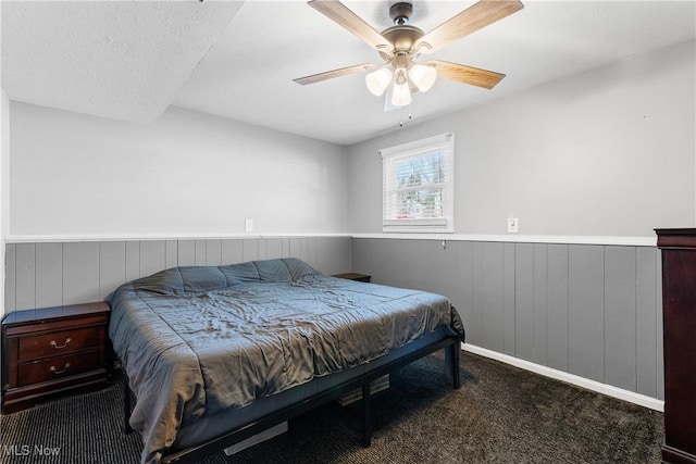 bedroom with ceiling fan, carpet, and wood walls