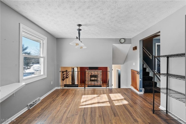 unfurnished living room featuring hardwood / wood-style floors, a fireplace, and a textured ceiling