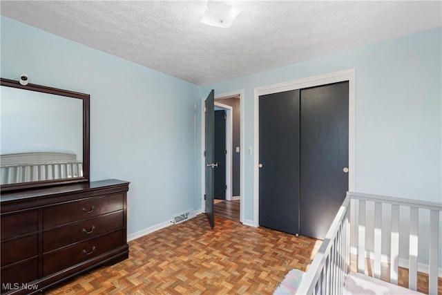 bedroom featuring a textured ceiling, a closet, and light parquet flooring