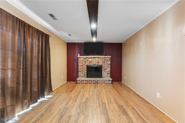 unfurnished living room featuring ornamental molding, a brick fireplace, and light wood-type flooring