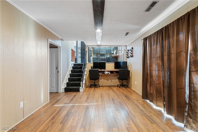 interior space featuring crown molding, wooden walls, and light wood-type flooring