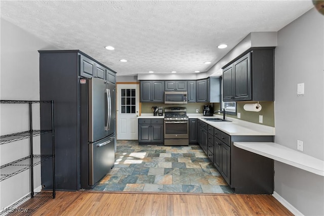 kitchen with sink, gray cabinetry, a textured ceiling, light wood-type flooring, and stainless steel appliances