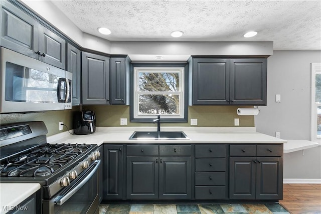 kitchen featuring dark hardwood / wood-style flooring, appliances with stainless steel finishes, sink, and a textured ceiling