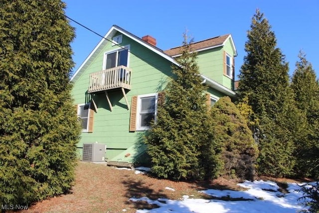 view of snowy exterior featuring cooling unit and a balcony