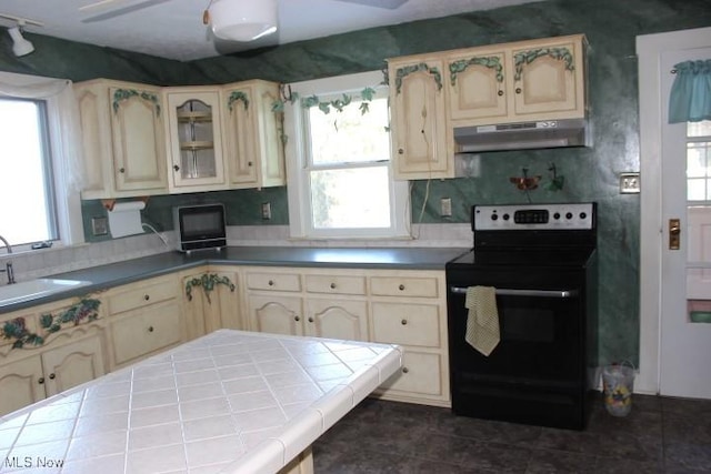 kitchen featuring plenty of natural light, black electric range oven, tile countertops, and ceiling fan