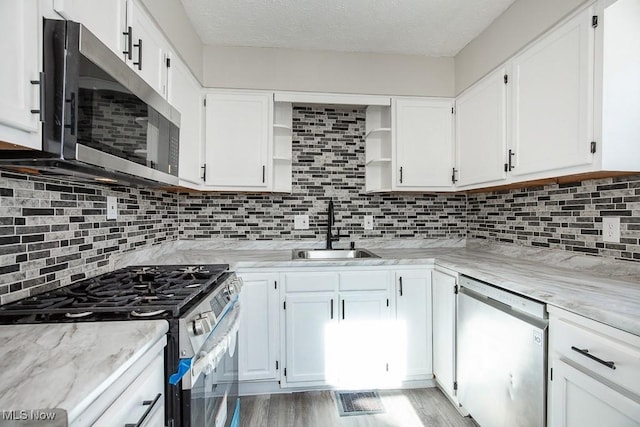 kitchen with appliances with stainless steel finishes, sink, white cabinets, and decorative backsplash