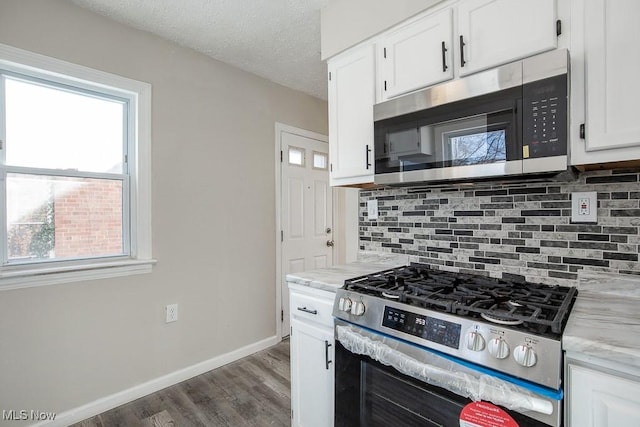 kitchen with a textured ceiling, dark hardwood / wood-style flooring, white cabinets, stainless steel appliances, and backsplash