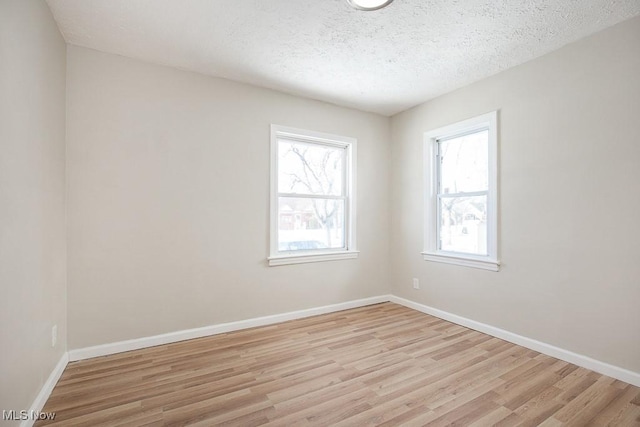 unfurnished room featuring a textured ceiling and light hardwood / wood-style flooring