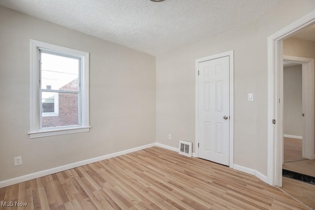 empty room with light hardwood / wood-style flooring and a textured ceiling