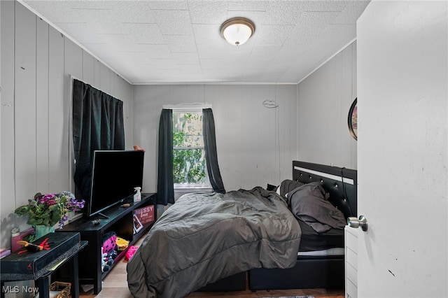 bedroom with wood-type flooring and wood walls