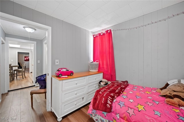 bedroom with hardwood / wood-style floors and wood walls