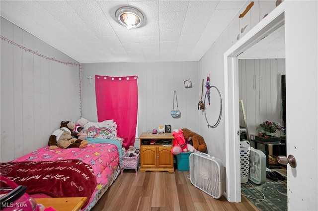 bedroom featuring wood-type flooring and wood walls