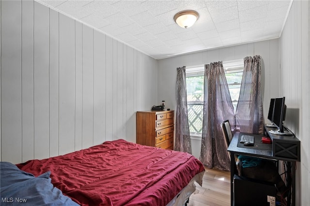 bedroom with hardwood / wood-style flooring and wood walls