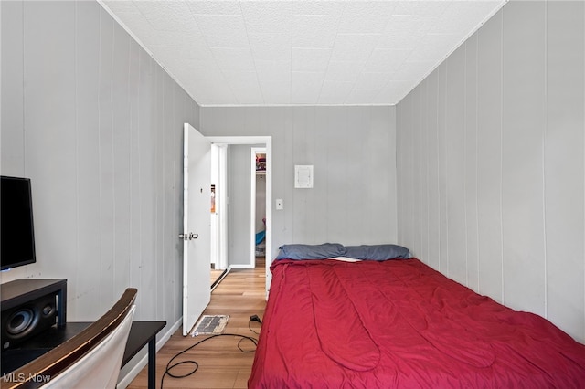 bedroom with wood-type flooring and wooden walls