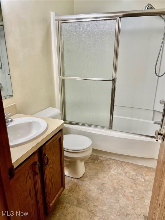 full bathroom featuring vanity, toilet, and bath / shower combo with glass door