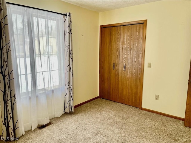 unfurnished bedroom with multiple windows, light colored carpet, and a closet