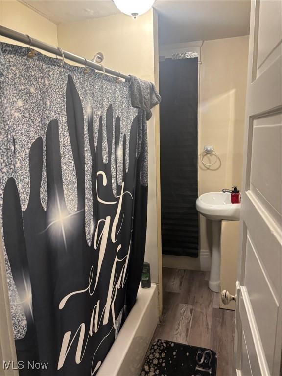 bathroom with hardwood / wood-style flooring, shower / tub combo with curtain, and sink