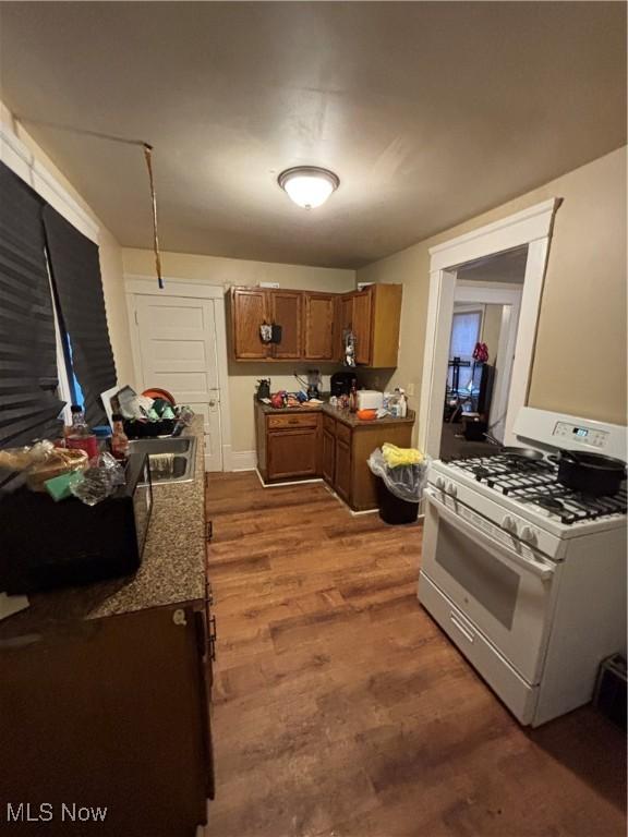 kitchen featuring stone countertops, white range with gas cooktop, and hardwood / wood-style floors