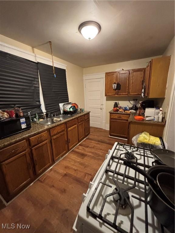 kitchen with dark wood-type flooring, sink, and white range with gas cooktop