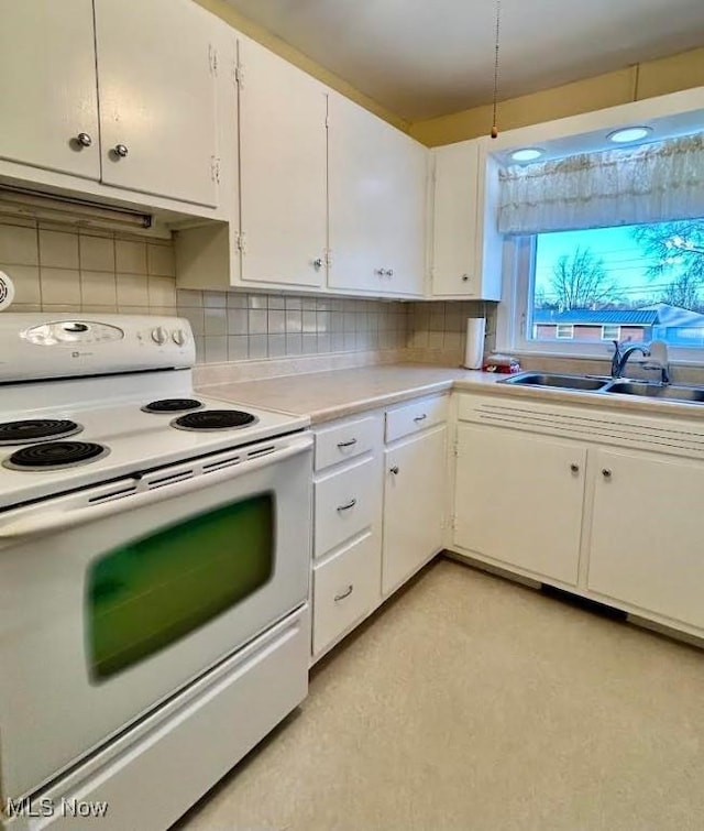 kitchen with tasteful backsplash, white cabinets, sink, and white range with electric stovetop