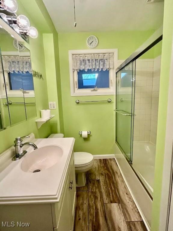 bathroom featuring a shower with door, wood-type flooring, vanity, and toilet