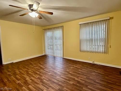 empty room featuring dark wood-type flooring and ceiling fan