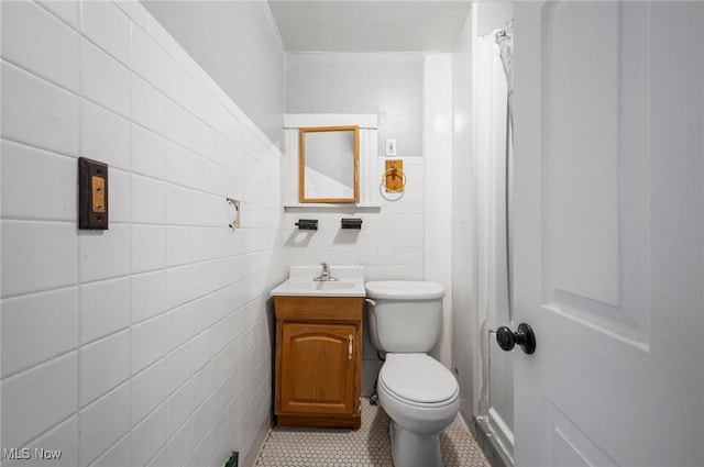 bathroom with tile walls, vanity, tile patterned floors, and toilet