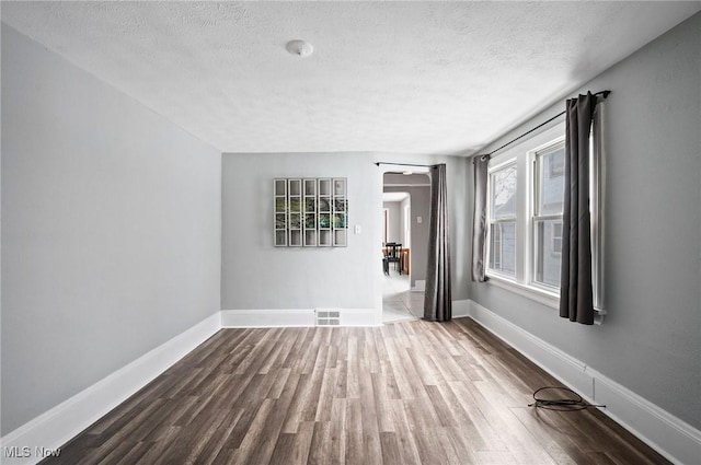 empty room with hardwood / wood-style floors and a textured ceiling