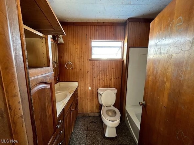 bathroom featuring wooden walls, vanity, and toilet