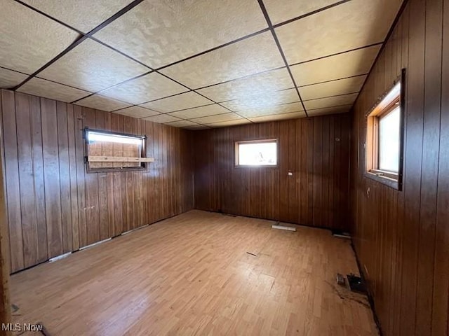 basement featuring light hardwood / wood-style flooring and wood walls