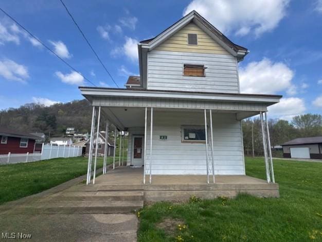 view of front facade featuring a porch, a front yard, and fence