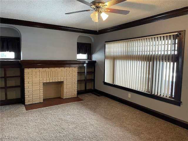 unfurnished living room with crown molding, a brick fireplace, a textured ceiling, ceiling fan, and carpet