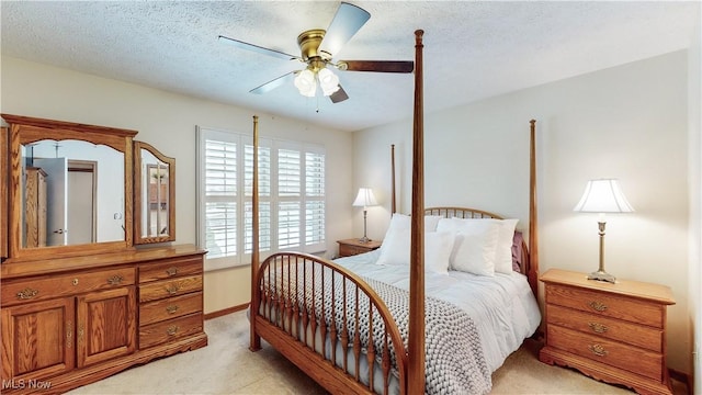 bedroom with ceiling fan, light colored carpet, and a textured ceiling